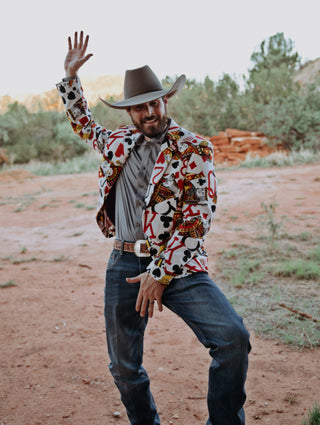 Modern cowboy in a vibrant patterned Espuela sport coat, styled with denim and boots in a natural western setting, highlighting bold statement western fashion
