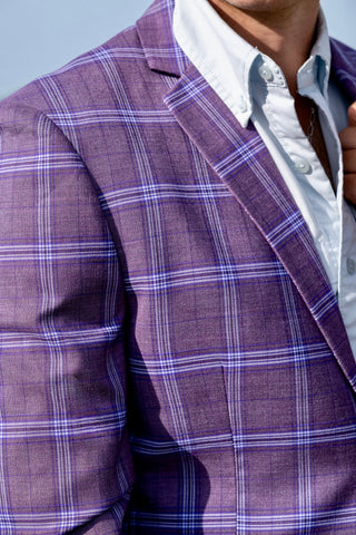 Close-up of a person wearing a purple plaid blazer over a white shirt.