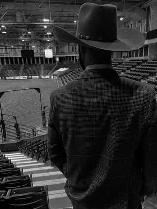 Cowboy wearing a tailored western sport coat and hat at a rodeo arena, modern cowboy style with premium fit and classic western wear