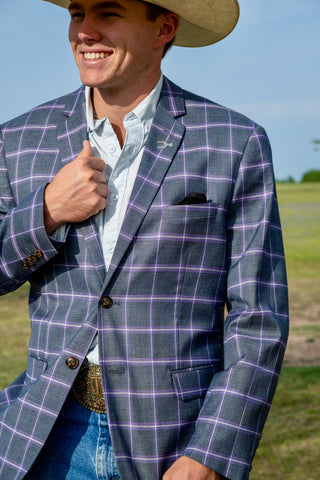 Man wearing a gray checkered blazer with a straw hat outdoors