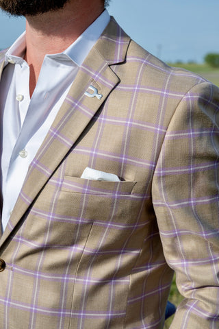 Man wearing a beige suit with purple checkered pattern outdoors