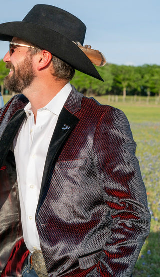 Man wearing a decorative jacket with intricate patterns outdoors.