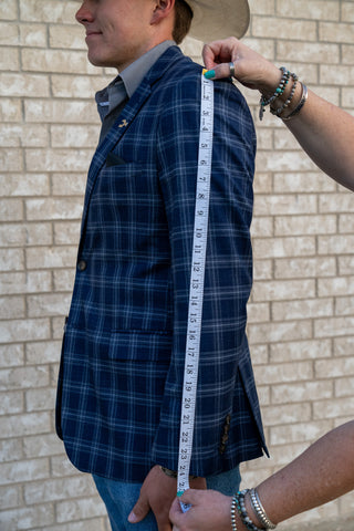 Man measuring sleeve length on blue plaid cowboy sport coat for western blazer sizing guide by Espuela Design Co