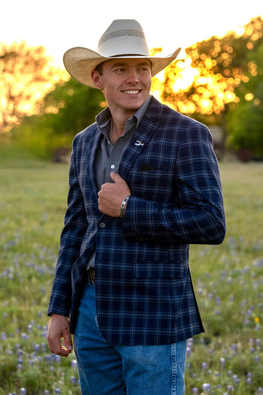 Man wearing a plaid jacket and cowboy hat standing in a field with sunset in the background. New Summer Cowboy Sport Coats .